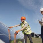 Een adviseur bespreekt energieoplossingen zoals zonnepanelen en laadpalen met een huiseigenaar voor een duurzame toekomst.
