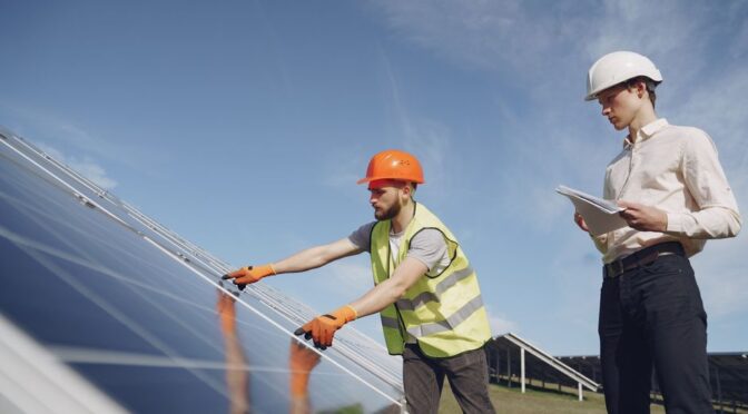 Een adviseur bespreekt energieoplossingen zoals zonnepanelen en laadpalen met een huiseigenaar voor een duurzame toekomst.